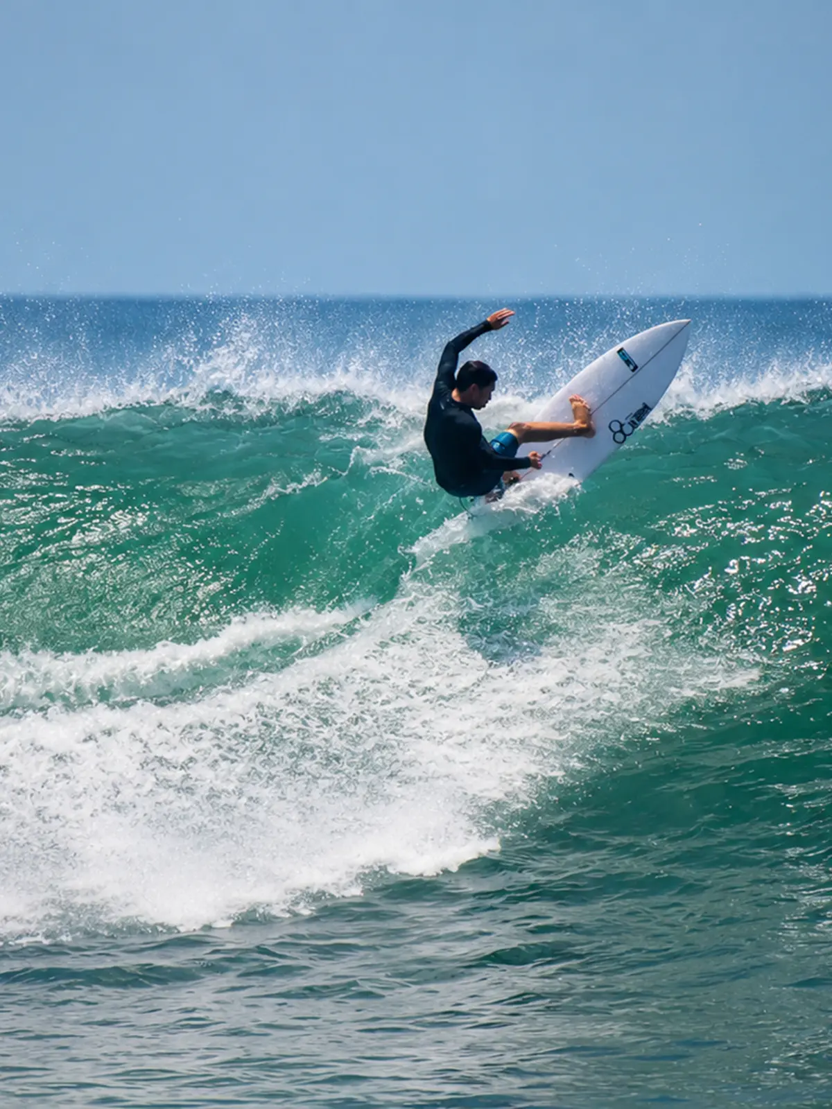 Surfer riding a white surfboard on a breaking ocean wave